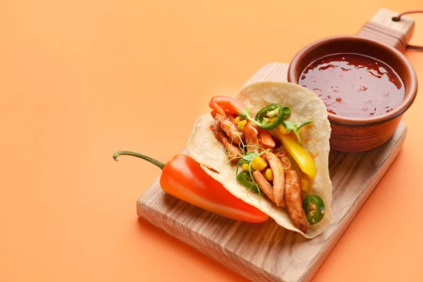 Bord mit leckerem frischen Taco und Sauce auf farbigem Hintergrund — Stockfoto