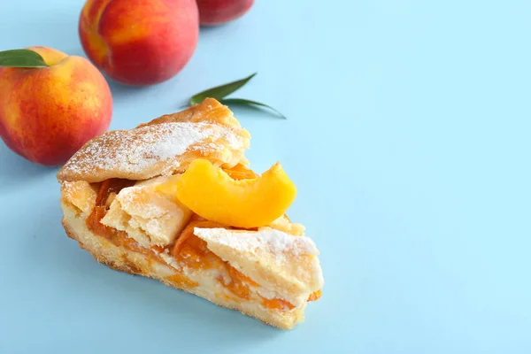 Piece of tasty peach pie on color background