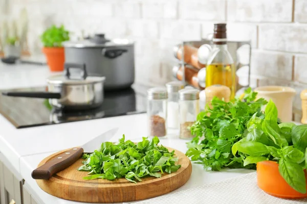 Skärbräda med kniv och färska örter på bord i köket — Stockfoto