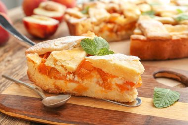 Ahşap arka planda lezzetli şeftali pasta parçası