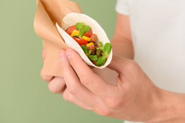 Renkli arka planda lezzetli taco ile Adam, closeup