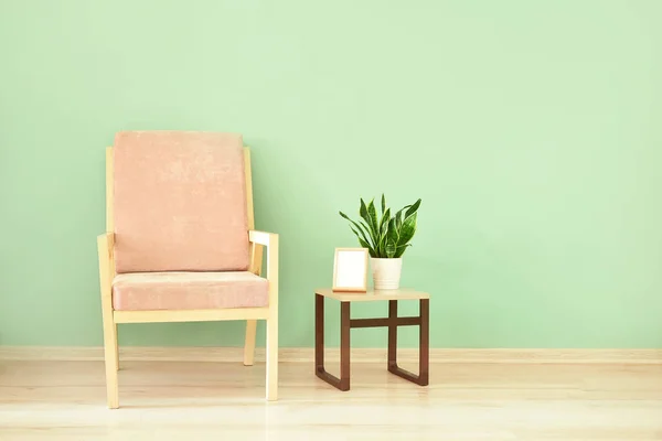 Modern armchair and table near color wall — Stock Photo, Image