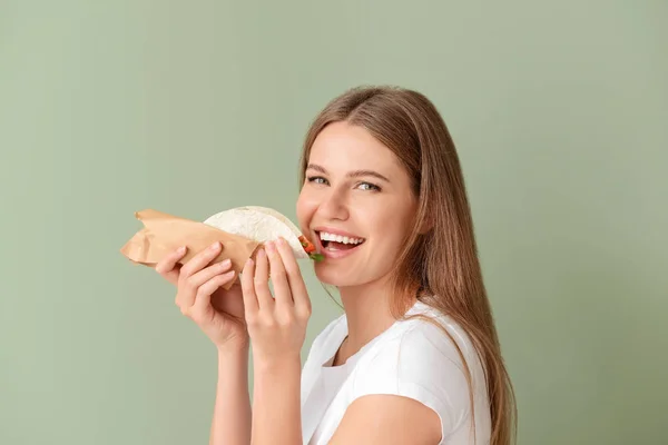 Woman eating tasty taco on color background — Stock Photo, Image