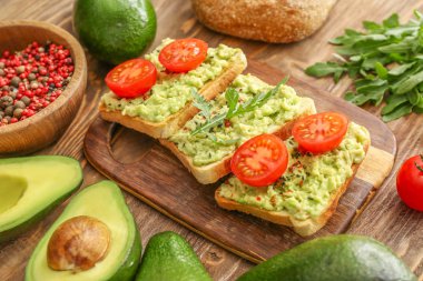 Ahşap arka planda püre avokado ve domates ile lezzetli sandviçler
