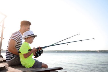 Baba ve oğul nehirde birlikte balık tutuyorlar.