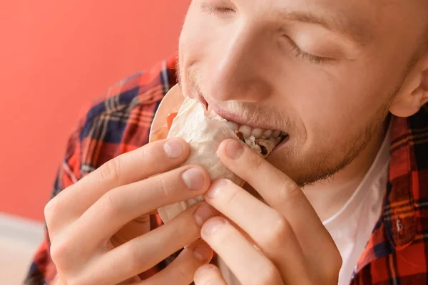 Hombre comiendo taco sabroso sobre fondo de color, primer plano — Foto de Stock