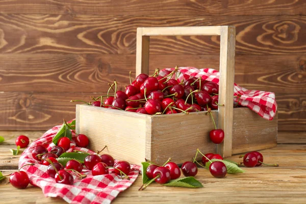 Basket with sweet ripe cherry on wooden table
