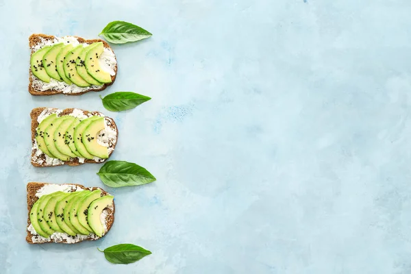 Lekkere broodjes met avocado op lichte kleur achtergrond — Stockfoto
