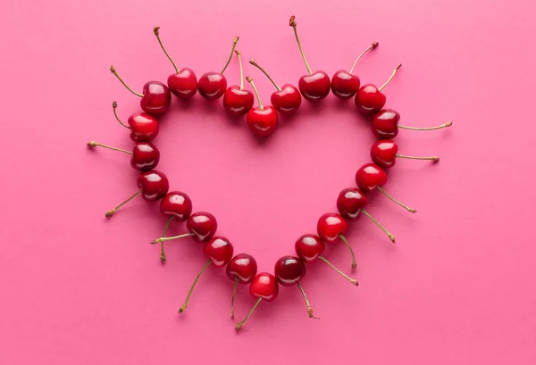 Serce ze słodkiej dojrzałej wiśni na kolorowym tle — Zdjęcie stockowe