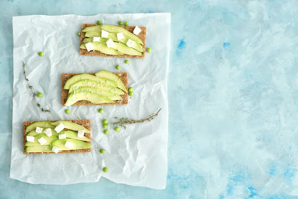 Tasty sandwiches with avocado and feta on light background