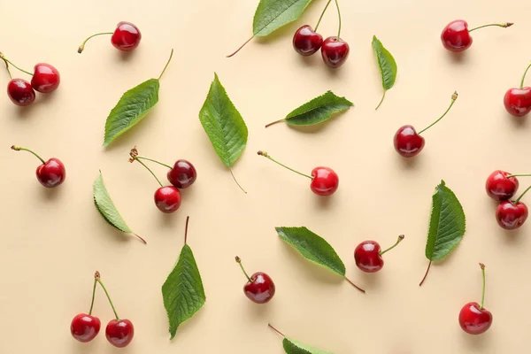 Sweet ripe cherry and leaves on color background — Stock Photo, Image