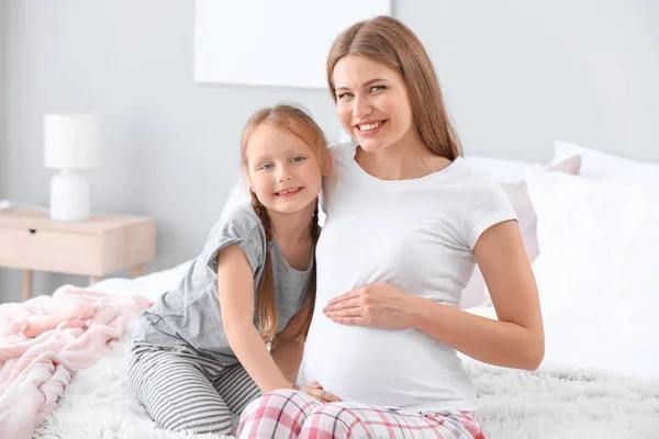 Gyönyörű terhes nő az ő kislánya a hálószobában — Stock Fotó
