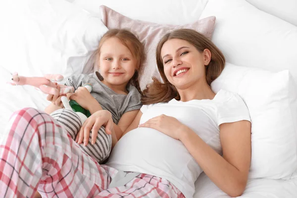 Yatak odasında küçük kızı ile güzel hamile kadın — Stok fotoğraf