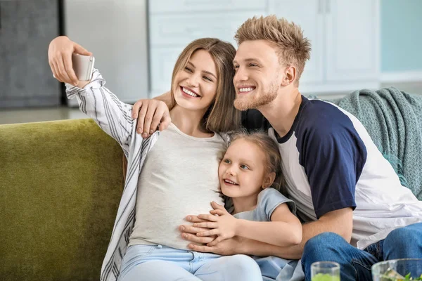 Beautiful pregnant woman with her family taking selfie at home — Stock Photo, Image