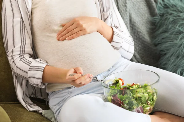 Krásná těhotná žena jíst salát doma — Stock fotografie