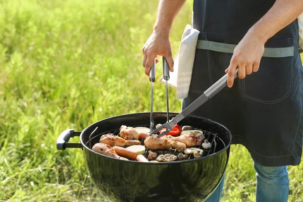 Man cooking tasty food on barbecue grill outdoors — Stock Photo, Image