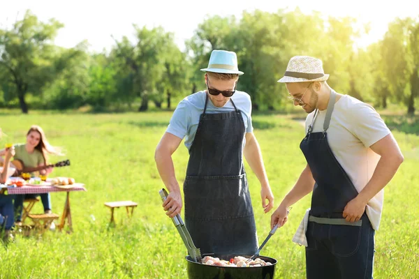 Friends cooking tasty food on barbecue grill outdoors — Stock Photo, Image