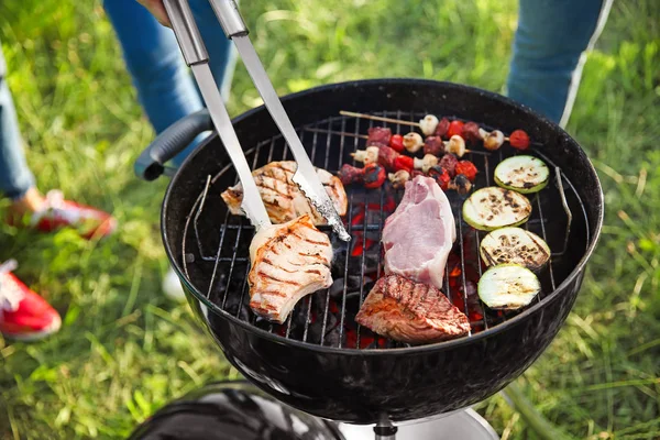 Přátelé vaříte chutné pokrmy na grilu venku — Stock fotografie