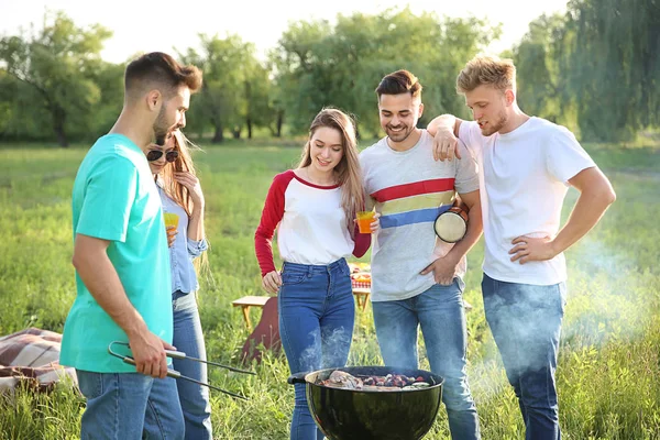 Přátelé vaříte chutné pokrmy na grilu venku — Stock fotografie