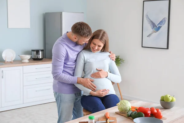 Portræt af lykkelige gravide par i køkkenet - Stock-foto