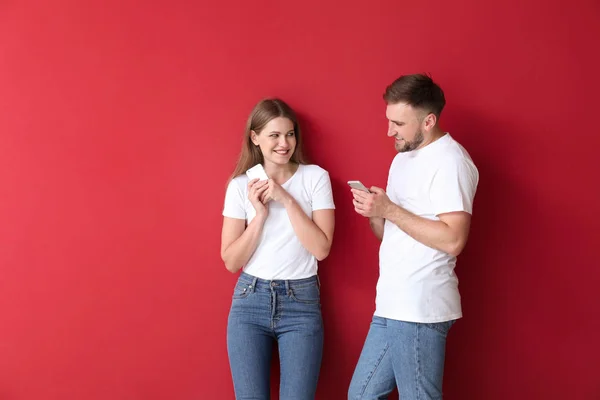 Portrét šťastný mladý pár s mobilními telefony na barevném pozadí — Stock fotografie