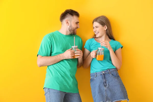 Retrato de pareja joven con cócteles sobre fondo de color — Foto de Stock