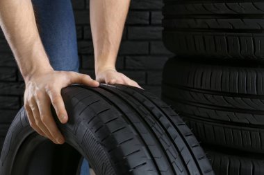 Karanlık duvara karşı araba lastikleri ile genç adam, closeup