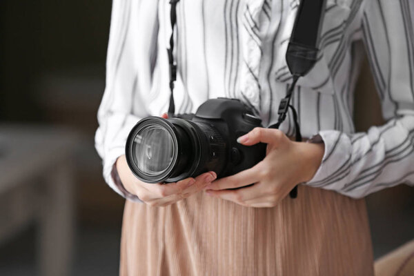 Young girl with modern photo camera at home, closeup