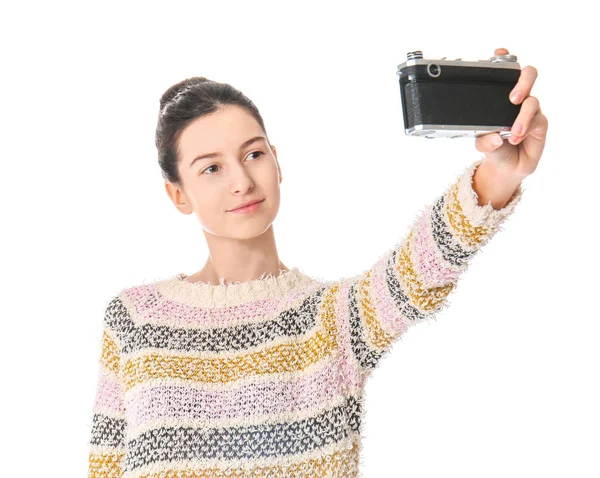 Young girl with photo camera taking selfie on white background — Stock Photo, Image