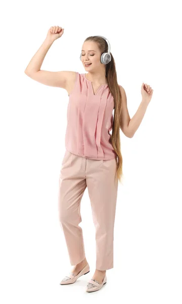 Beautiful young woman listening to music and dancing against white background — Stock Photo, Image