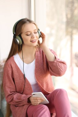 Evde müzik dinleyen güzel genç bir kadın.