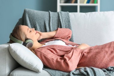 Evde müzik dinleyen güzel genç bir kadın.