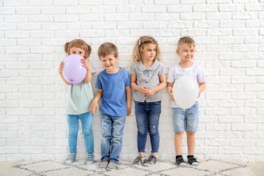 Beyaz tuğla duvara yakın hava balonları ile Sevimli küçük çocuklar