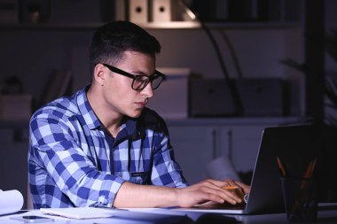 Meşgul genç adam akşam geç saatlerde evde çalışıyor