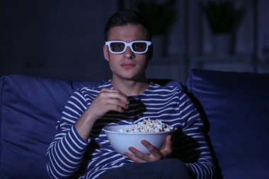 Genç adam gece geç saatlerde Tv izlerken patlamış mısır yeme