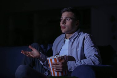 Genç adam gece geç saatlerde Tv izlerken patlamış mısır yeme