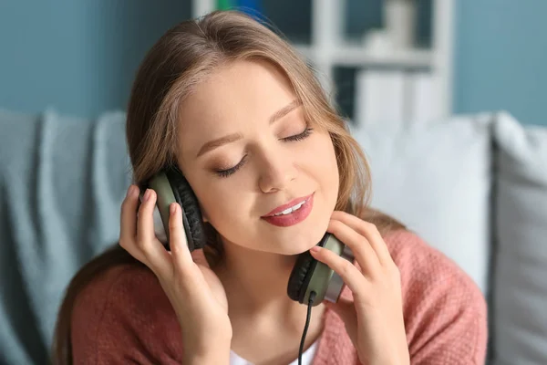 Beautiful young woman listening to music at home — Stock Photo, Image