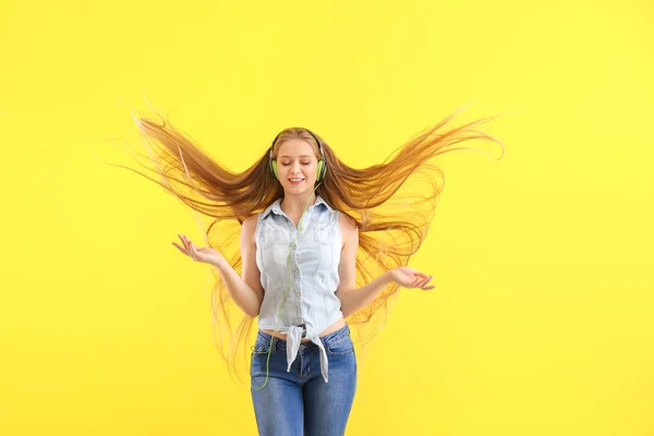 Belle jeune femme écoutant de la musique et dansant sur fond de couleur — Photo