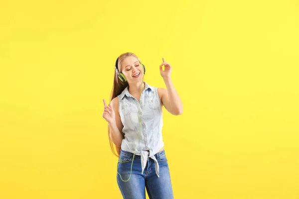 Schöne junge Frau hört Musik und tanzt vor farbigem Hintergrund — Stockfoto