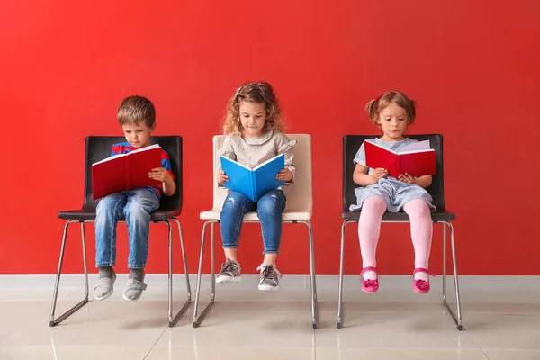 Petits enfants mignons lisant des livres près du mur de couleur — Photo