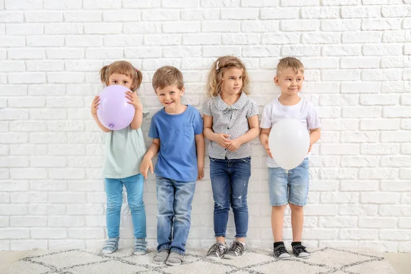 Beyaz tuğla duvara yakın hava balonları ile Sevimli küçük çocuklar