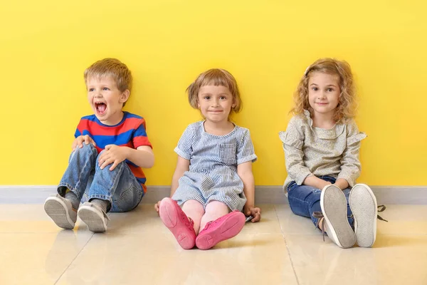 Cute little children sitting near color wall — Stock Photo, Image