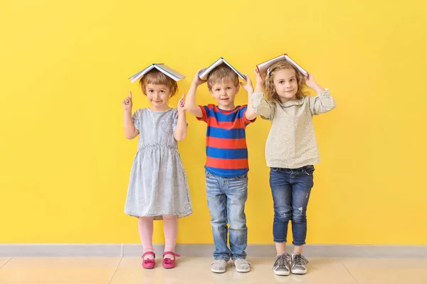 Lindos niños pequeños con libros cerca de la pared de color — Foto de Stock