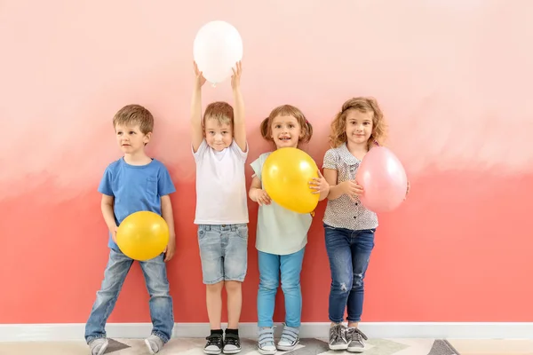 Śliczne małe dzieci z balonami w pobliżu koloru ściany — Zdjęcie stockowe