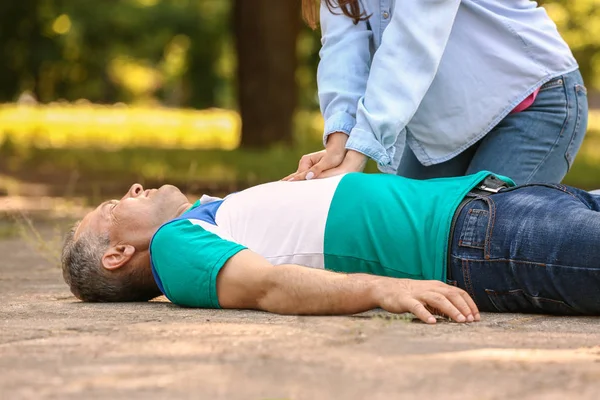 Female passer-by doing CPR on unconscious mature man outdoors — Stock Photo, Image