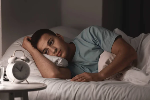 밤에 침대에 누워있는 동안 불면증으로 고통받는 젊은 남자 — 스톡 사진