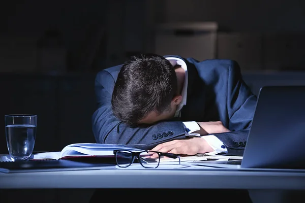 Уставший бизнесмен спит за рабочим столом поздно вечером — стоковое фото
