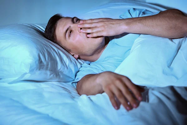 Jovem sofrendo de insônia enquanto estava deitado na cama à noite — Fotografia de Stock