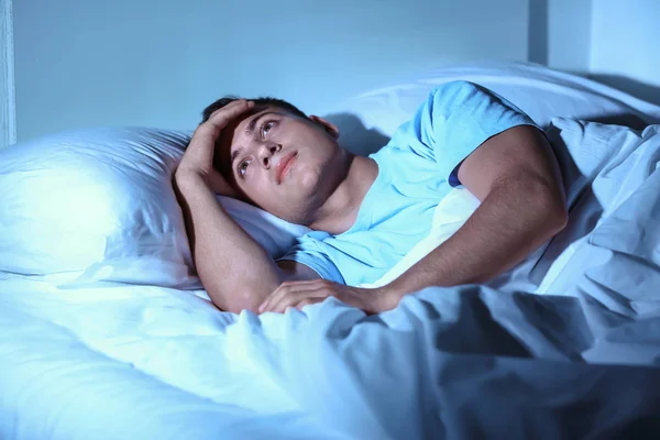 Young man suffering from insomnia while lying in bed at night — Stock Photo, Image