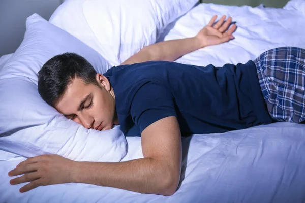 Joven durmiendo en la cama por la noche — Foto de Stock